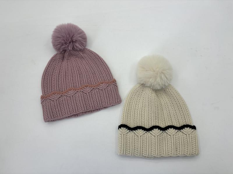 Dwie czapki beanie z pomponem: różowa z rdzawym wykończeniem i kremowa z czarnym, obie z prążkowanej dzianiny.