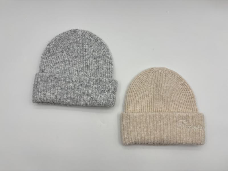 Dwa czapki beanie z prążkowanej wełny z podwiniętym mankietem – szara i beżowa, na białym tle.