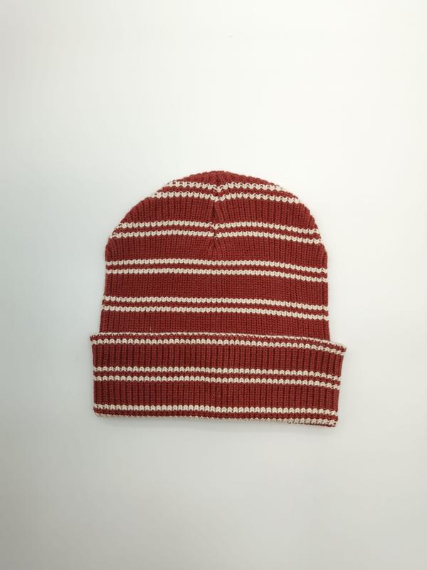 Czapka beanie w rdzawoczerwone i kremowe poziome prążki z podwiniętym mankietem, widok z góry.