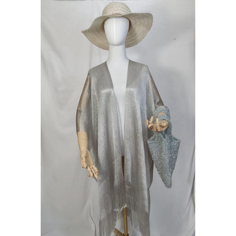 Manekin w srebrnym metalicznym kimono z frędzlami, otwarty przód, słomkowy kapelusz i niebieska brokatowa torebka.