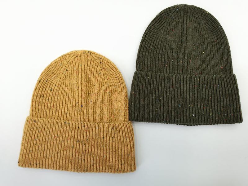 Dwie prążkowane czapki beanie z wywiniętym mankietem w kolorze musztardowym i oliwkowym z melanżowym wzorem, na białym tle.