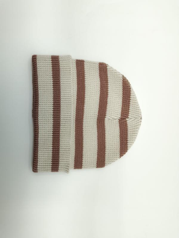 Kremowo-brązowa prążkowana czapka beanie w paski, złożona, widok z góry na białym tle.