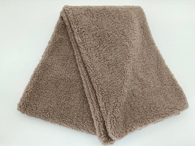 Miękki koc sherpa z polaru w kolorze taupe, puszysty i przytulny koc typu throw do salonu.