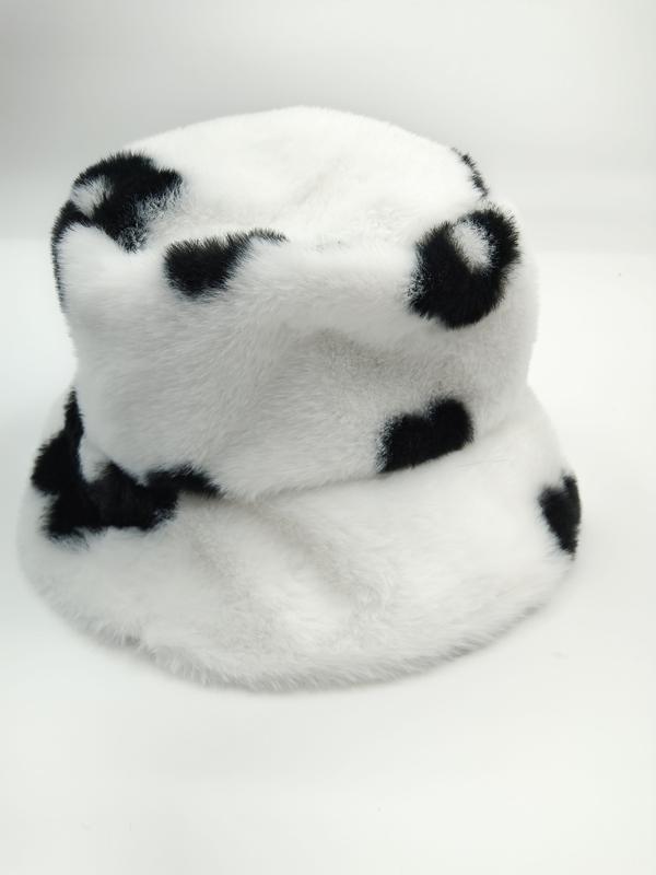 Biały bucket hat z futra syntetycznego z czarnym wzorem w łaty krowy, zdjęcie na białym tle.
