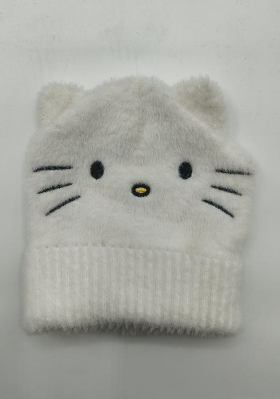 Biała puszysta czapka beanie z dzianiny z wyhaftowaną kocią twarzą, wąsami i uszkami, złożona na białym tle.