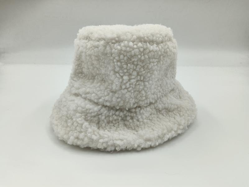 Biały pluszowy kapelusz typu bucket z szerokim rondem i fakturą teddy fleece na białym tle.